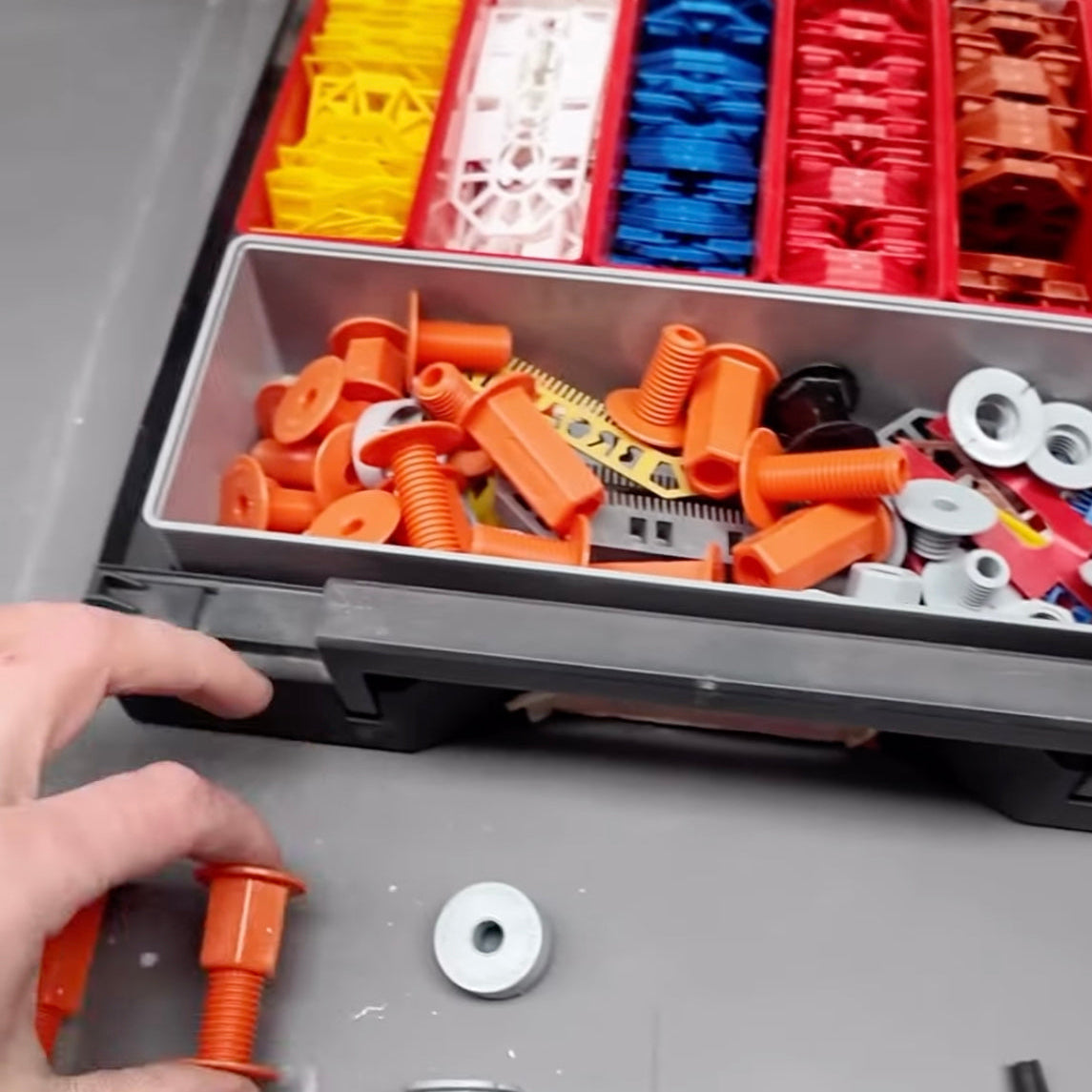 Professional kitchen cabinet fixing components and adjustable spacer fixings organised in a toolbox during a kitchen installation setup