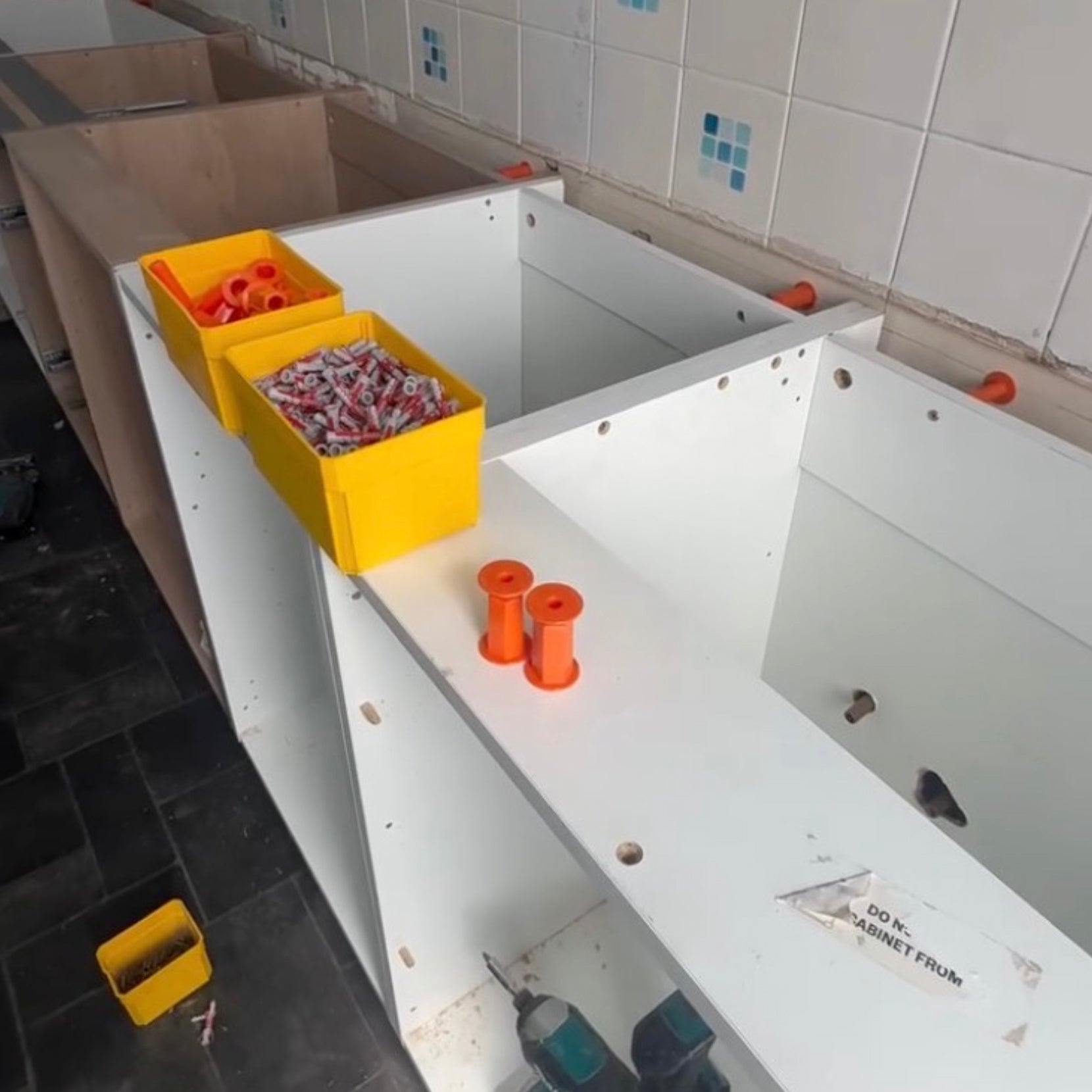 Installation de meubles de cuisine avec des fixations réglables Space-Plug, permettant un réglage précis et une compensation des irrégularités du mur.